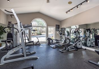 a gym with cardio machines and other exercise equipment and a window